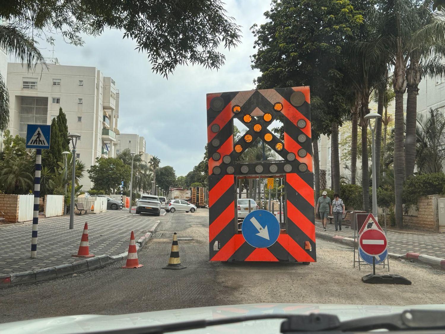 עגלת חץ של דרכי נועם מוצבת בשכונה בזמן עבודות, עם חץ מכוון ותמרור כחול