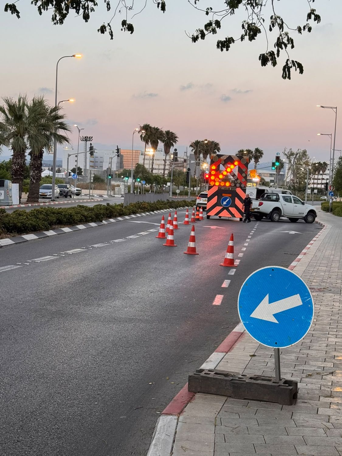 עגלת חץ וקונוסים בשעת בין ערביים על כביש ראשי